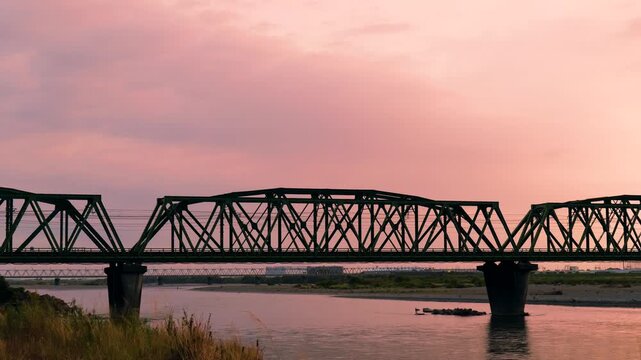 夕暮れ時の鉄道の橋を渡る列車
