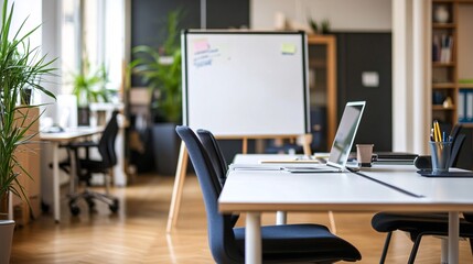 Open office workspace with a whiteboard, laptop, and a plant.
