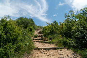 A footpath with wooden stairs in for easy mountain climbing. Rila mountain, Bulgaria. Clear blue sky with gentle clouds.