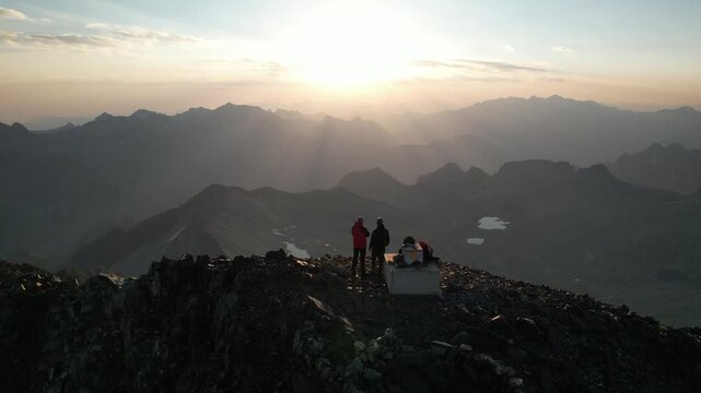 Dos personas alpinistas en la cima de una monta&ntilde;a en el amanecer o atardecer