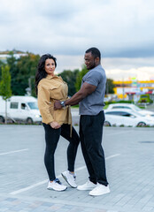 Couple posing playfully in a parking lot during early evening. A couple playfully interacts in a parking lot during dusk.