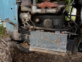 The engine compartment of an old tractor with a battery motor and an exhaust gas exhaust system. Agricultural machinery background and metal tractor structure.