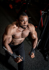 Bodybuilder performing cable fly exercise in a gym at night. A bodybuilder intensely performs a...