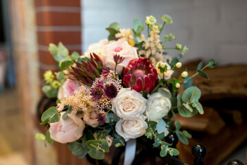 Cozy interior with a stunning rose and protea arrangement. A lovely bouquet combines roses, protea, and greenery, enhancing a warm ambiance.