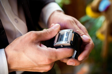 Man adjusting a vintage wristwatch in a cozy indoor setting. A man carefully adjusts a vintage wristwatch while seated indoors.