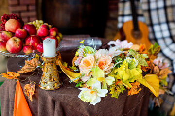 Autumn floral arrangement and fruits on a rustic table setting. A vibrant display of flowers and fresh fruits on a cozy table in autumn.