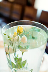 Fresh white and yellow flowers in a clear vase with water. A clear vase holds white and yellow flowers submerged in water.