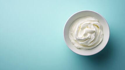 A simple shot of Greek yogurt in a white bowl, isolated on a solid color background with room for text on the side.