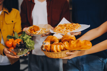 Happy friends making a toast with beer before eating pizza in a shared apartment.