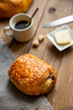 Pain au chocolat ou chocolatine sur le plateau en bois d'un petit d&eacute;jeuner.