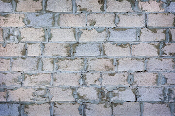 Unfinished brick wall with exposed mortar. A close-up of an unfinished brick wall, featuring exposed mortar and rough, unpolished bricks.