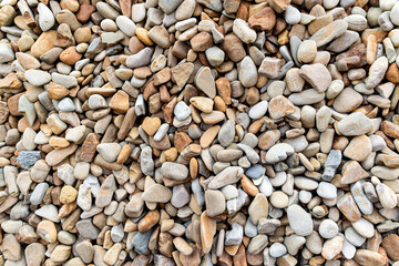 Assorted smooth stones in various earthy tones. A close-up of assorted smooth stones in various earthy tones, ranging from beige and gray to light brown.