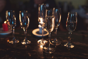 gasses of champagne in the dark with candles light. alcohol cocktails on a party. Party and holiday celebration concept.