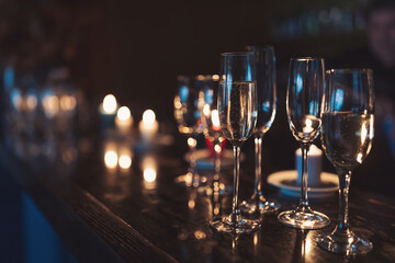 gasses of champagne in the dark with candles light. alcohol cocktails on a party. Party and holiday celebration concept.
