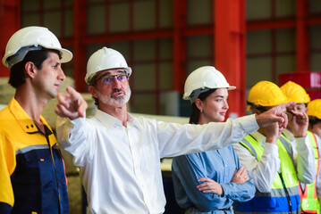 Professional Caucasian manager engineer wearing white helmet is training industry factory worker, workshop operator, mechanical engineering team production in heavy industrial manufacture factory.