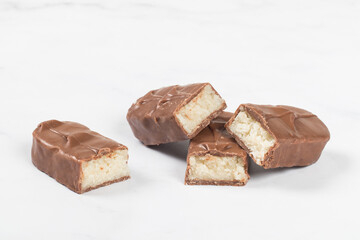 Candy bar with coconut pulp, in milk chocolate. Dark background. White background