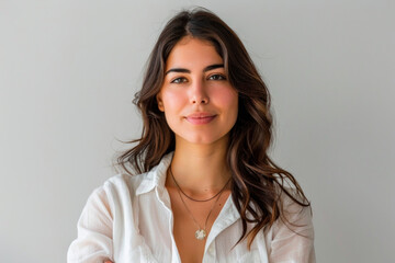Fototapeta premium Young woman smiling confidently in a light-colored blouse against a neutral background