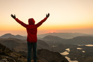 Fototapeta premium A person is standing on a mountain top, looking out at the sunset