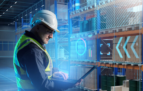 Man engineer is standing in warehouse. Software development for logistics center. Engineer with laptop in warehouse building. Development of goods accounting system. Man inside automated warehouse