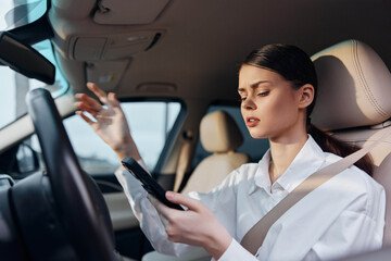 Woman driving holding cell phone a woman is seated in the driver's seat of a car, one hand on the steering wheel and the other holding a cell phone, illustrating the concept of distracted driving