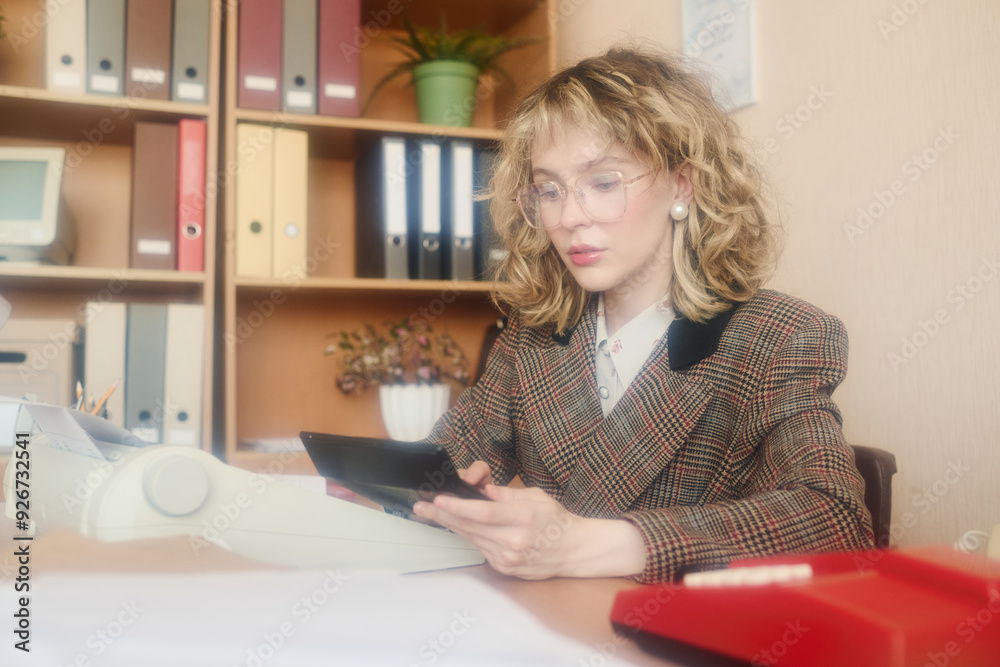 Poster woman focusing on reviewing documents while seated at office desk. background includes shelves with 