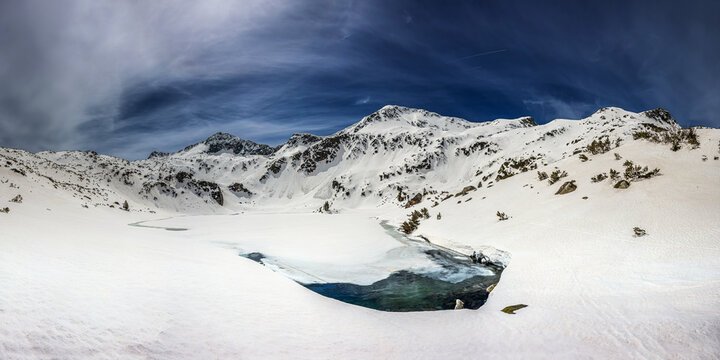 Panoramic view of the Banderishko Ribno lake and the mountains around it under the snow in winter sunny day.