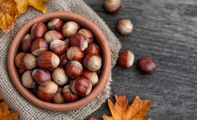 Freshly gathered chestnuts in a rustic bowl on a textured surface with autumn leaves