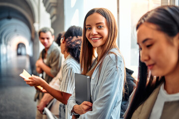 Portrait of a happy young confident modern female student among classmates. College studies, preparation for studies, admission, exams.