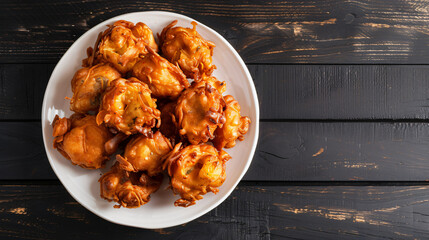 Crispy onion bhajis are served hot on a white plate, offering a tempting taste of indian street food