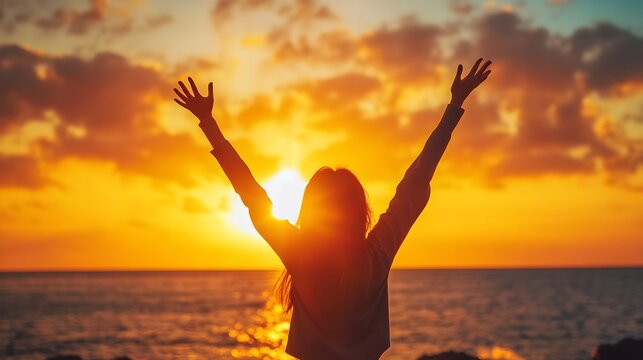woman cheering at sunrise by the beach with outstretched arms - Powered by Adobe