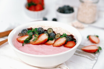 Presented by fruits putting yogurt toppings with strawberry, berry, oats, raisins and chia seed decorated by peppermint in white blow. Pink background. Set of healthy dairy product choice. Pecuniary.