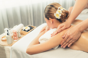 Caucasian woman customer enjoying relaxing anti-stress spa massage and pampering with beauty skin recreation leisure in day light ambient salon spa at luxury resort or hotel. Quiescent