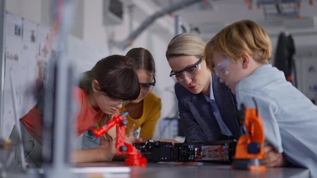 Children learning robotics in Elementary school. Young students building robot in after school robotics club. Field trip to real robotics laboratory.