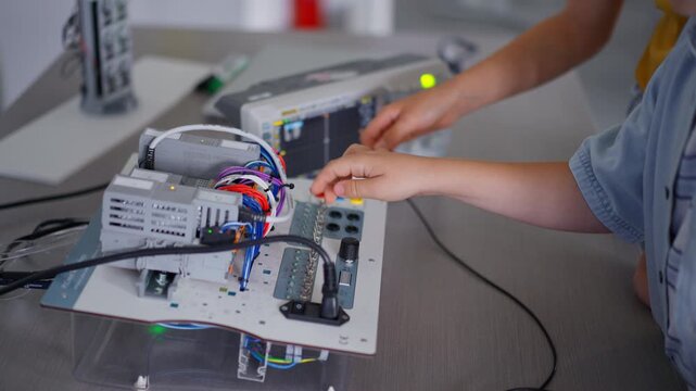 Close up of wo classmates working togeter on circuit board, building robot in after-school robotics club. Children learning robotics in Elementary school.