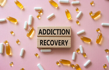 Addiction Recovery symbol. Concept words Addiction Recovery on wooden blocks. Beautiful pink background with pills. Medicine and Addiction Recovery concept. Copy space.