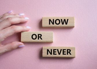 Now or Never symbol. Concept words Now or Never on wooden blocks. Businessman hand. Beautiful pink background. Business and Now or Never concept. Copy space