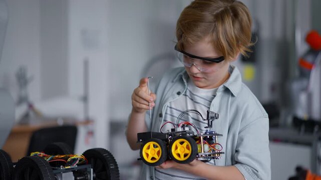 Portrait of schoolboy building robotic car in after-school robotics club. Children learning robotics in Elementary school. Science for kids.