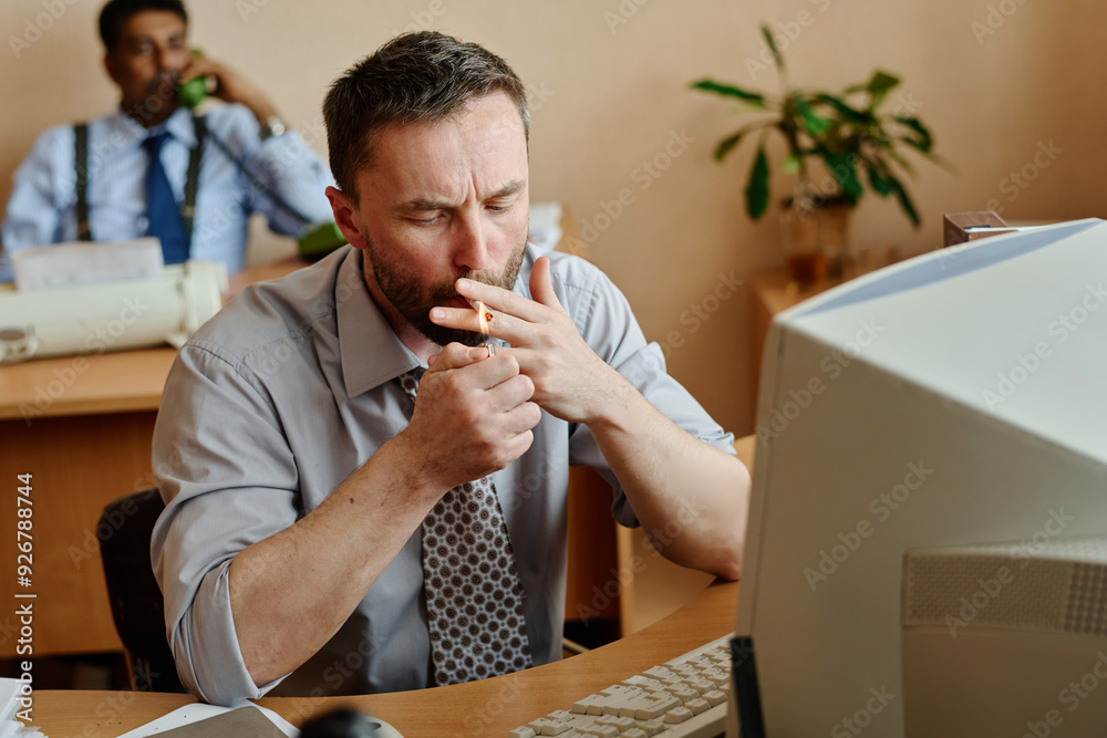 Aufkleber man sitting at desk in office, managing stress by smoking while colleague works in background with p