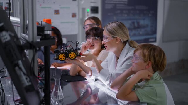 Children learning robotics in Elementary school. Young students building robot in after school robotics club. Field trip to real robotics laboratory.