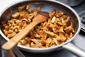 Sauted Chanterelle Mushrooms in a Skillet with Wooden Spoon