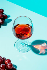 top view of glass of red wine and ripe grapes on blue background