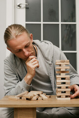Man player balances wooden blocks, trying not to topple the tower in a competitive game setting