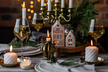 Rustic Scandinavian style zero waste eco-friendly dinner table decor for Christmas or new year family celebration. Wooden table, natural elements like pine cones, fir tree branches, candles