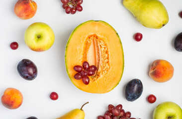 A variety of fruits, melon, apple, pear, grapes and peach on a light background. Composition of fruits. Top view, horizontal..