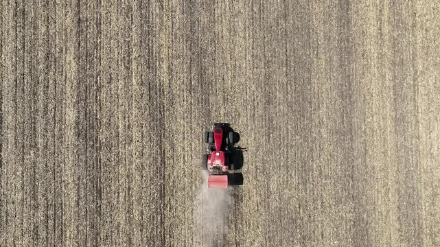 red tractor working with fertilizers spreader on the field