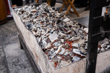 On top of a wooden table, there is a substantial pile of charcoal that has been carefully placed, showcasing the contrast between the dark charcoal and the light wood surface underneath it