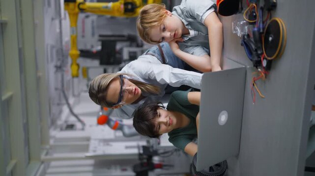 Children learning robotics in Elementary school. Young students programming, building robot in after school robotics club. Field trip to real robotics laboratory. Vertical view.