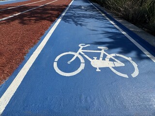 Separate bicycle lane for riding bicycles.Bicycle icon on the lane .New public asphalt bicycle lane close up beside the road.White painted bike on asphalt.