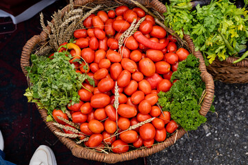 A beautiful and vibrant basket overflowing with ripe, juicy tomatoes and an array of fresh, colorful vegetables, showcasing the wonderful bounty of natures harvest from a local greengrocer