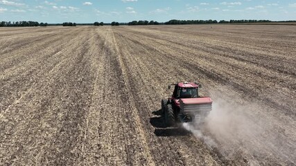 slow motion of red tractor spreading mineral fertilizer on a field